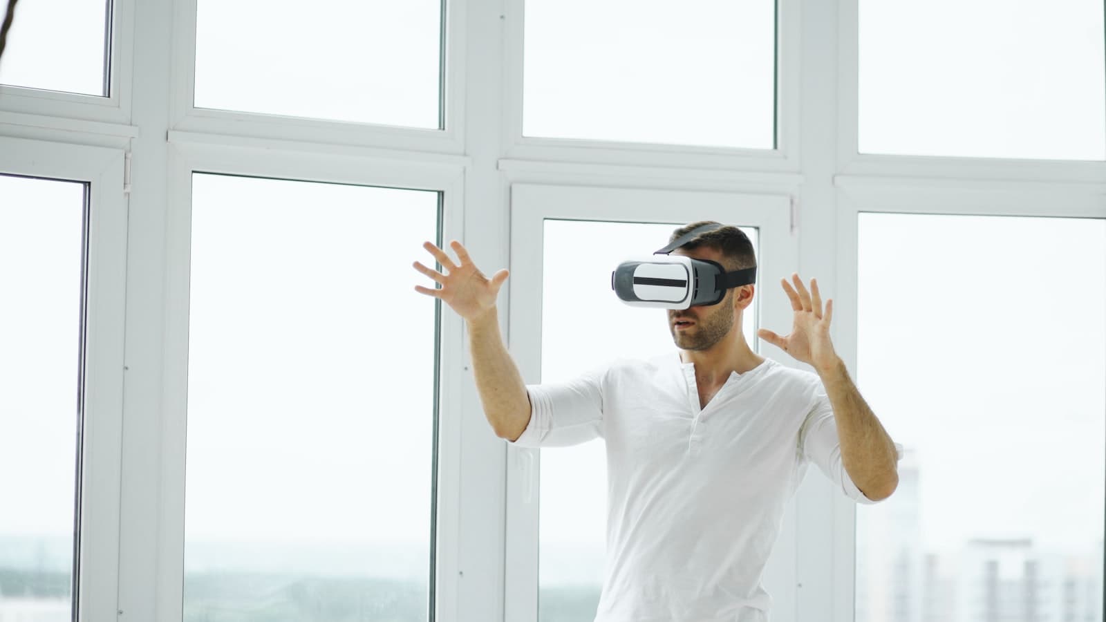 Person wearing a VR headset with hands raised, mimicking remote-control gestures